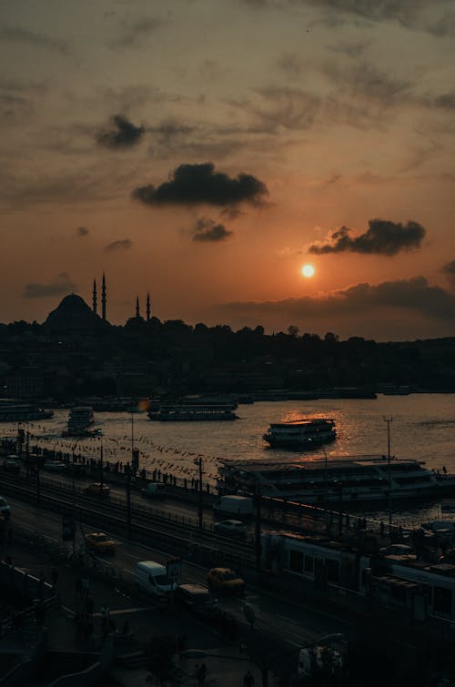 Free Picturesque view of golden sunset over old town pier with ships near road in cloudy evening Stock Photo