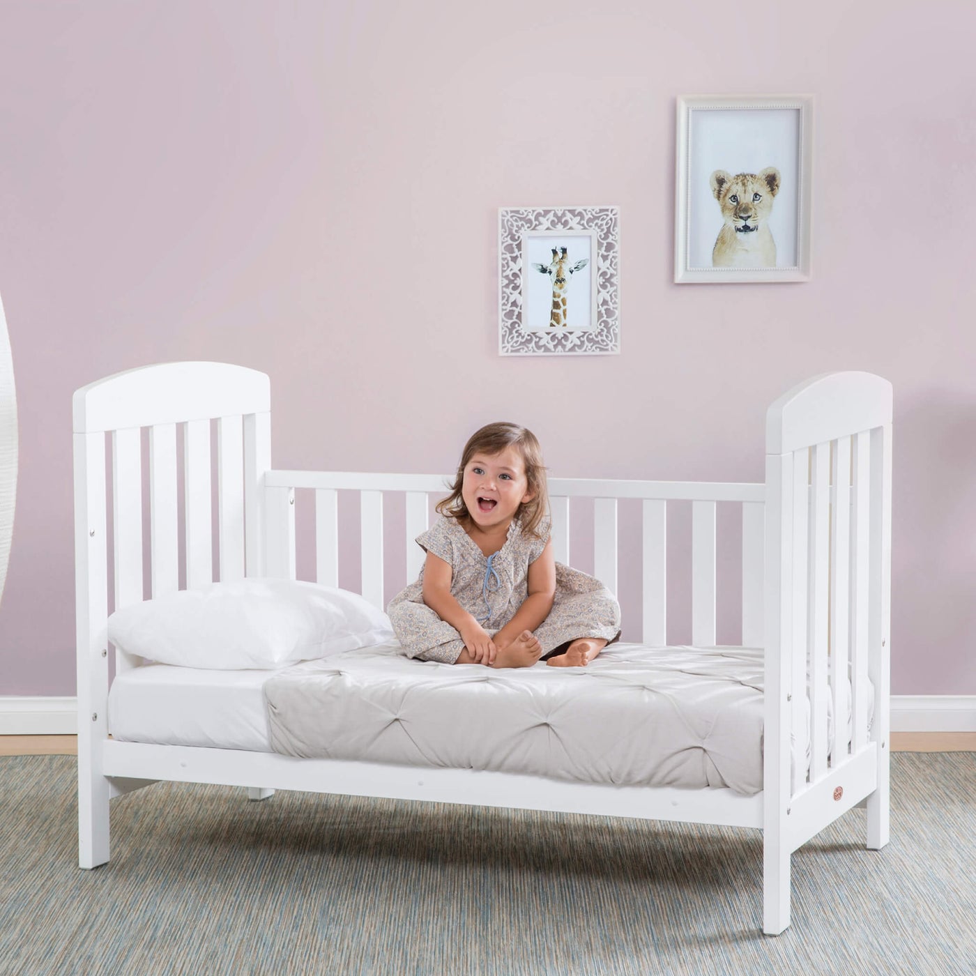 Alice cot bed with a child sitting on the mattress