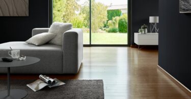 Salón luminoso con suelo de madera y muebles claros