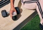 Person holding a Spacegoods tumbler beside outdoor training equipment